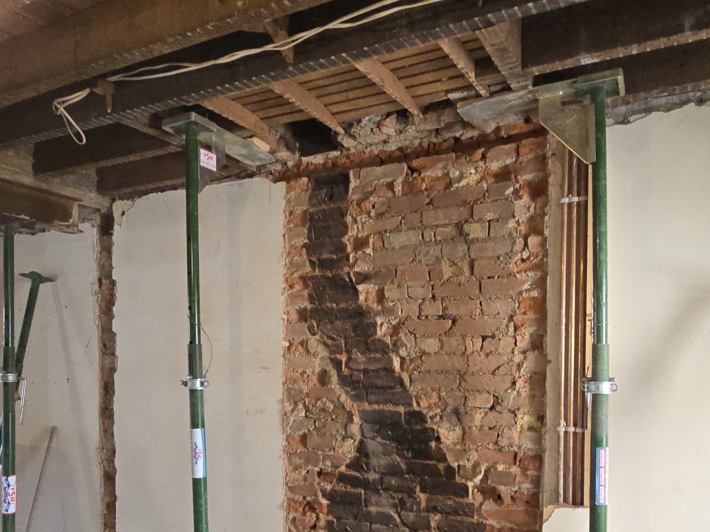 A chimney breast removed at ground floor with the stack above propped and the brickwork exposed.