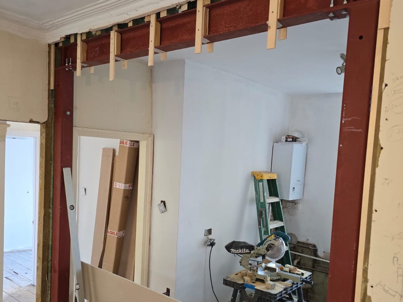 A steel goalpost frame installed by GS Renovation, with the engineer's sizing notes pencilled on the wall alongside
