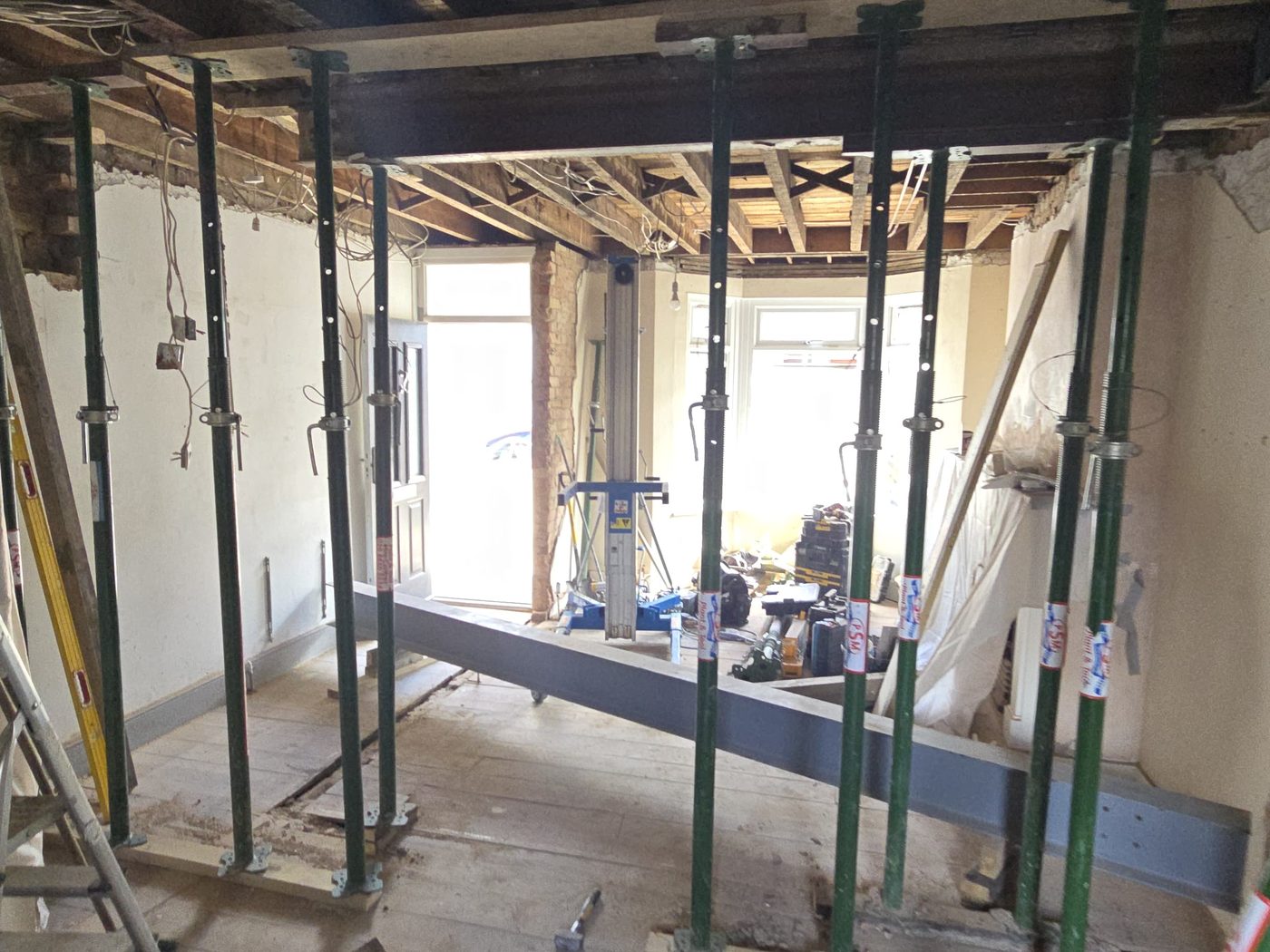 A wide structural opening propped by GS Renovation with the steel beam on the floor ready to be lifted
