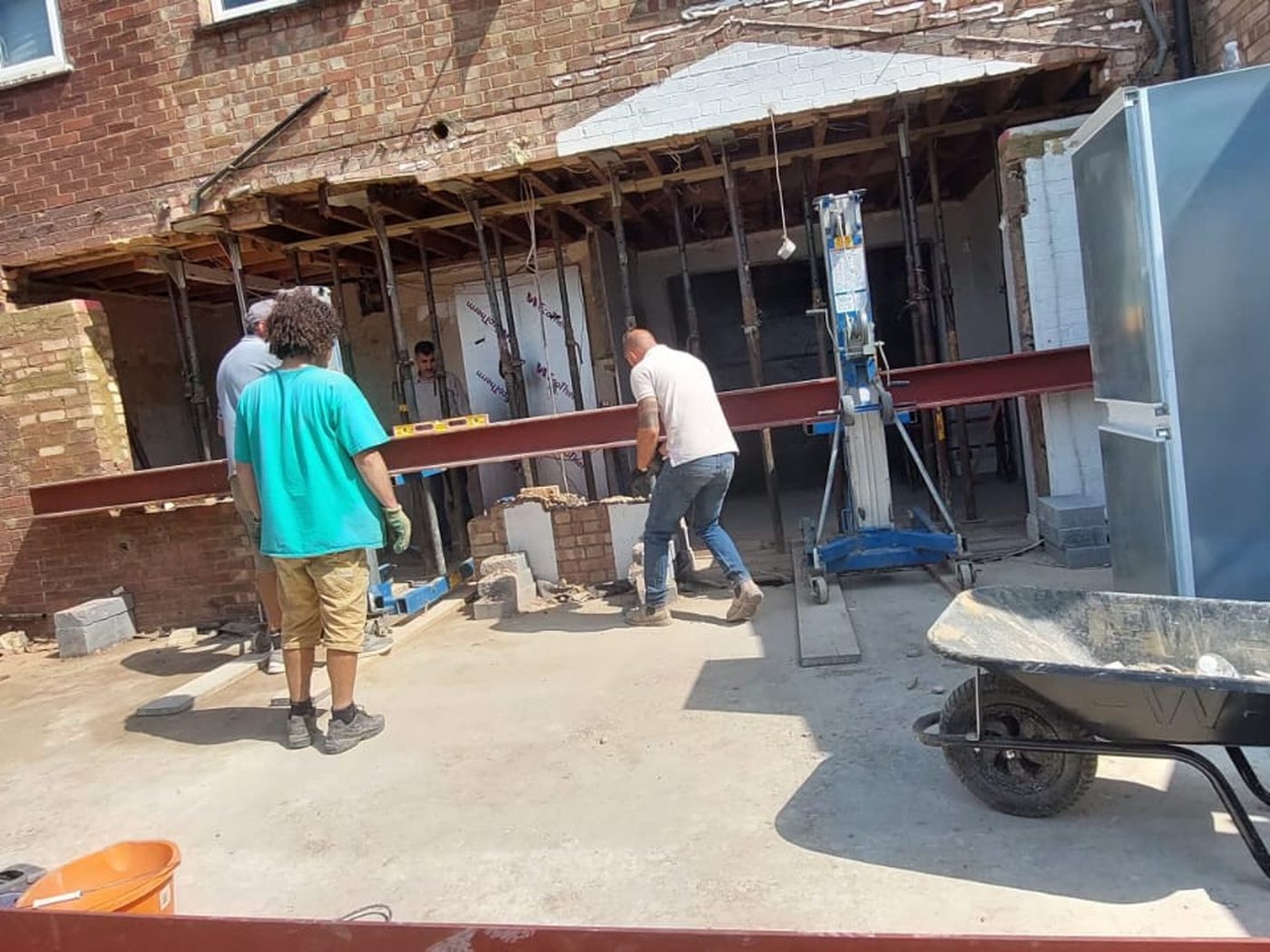 GS Renovation tradesmen positioning a steel beam beside a propped structural opening on a London rear elevation