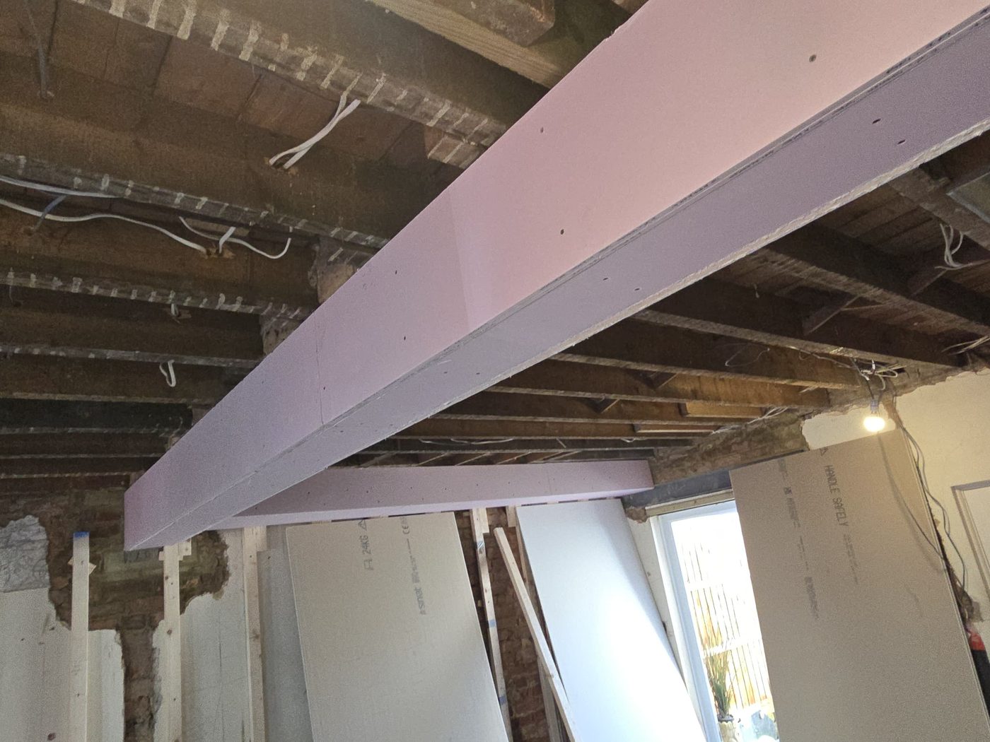 A steel beam encased in fire-rated board by GS Renovation, ready for skimming
