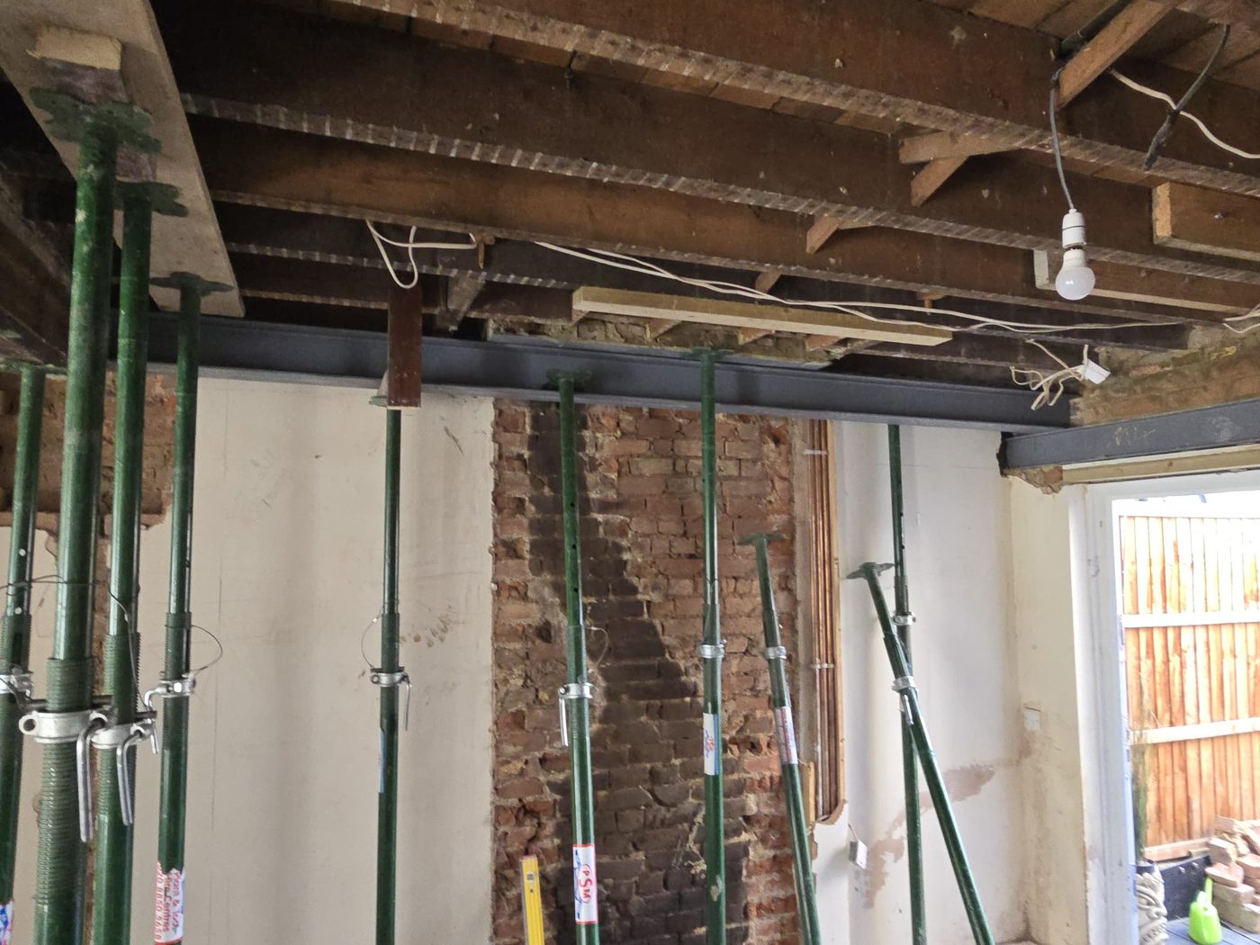 A steel beam installed by GS Renovation across a knocked-through opening, bearing onto an exposed brick pier